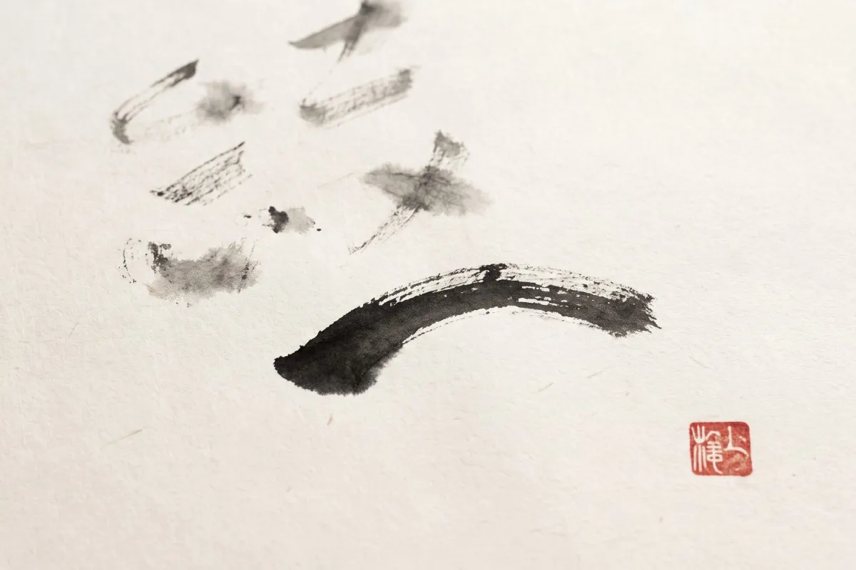 Black ink brushstrokes and a thick curved sweep on textured cream paper, with a small red seal stamp.