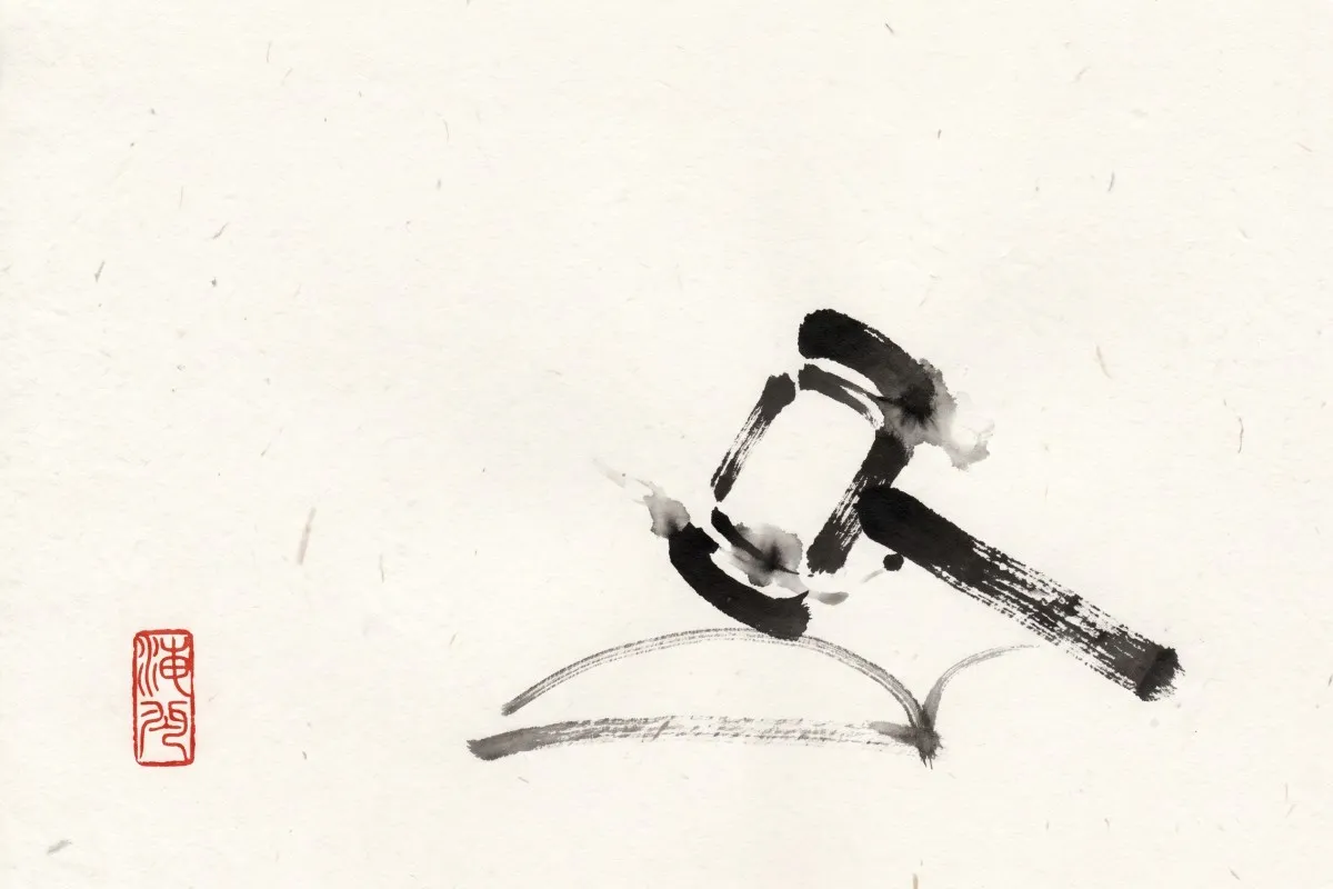 Brush-and-ink drawing of a gavel resting on an open book, with a small red seal stamp at the left.
